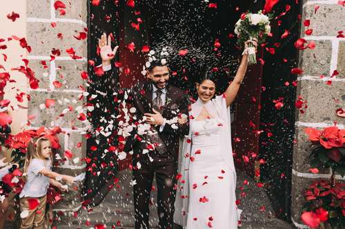 Fotógrafo de bodas en Tenerife, novios saliendo de la iglesia entre pétalos de rosas