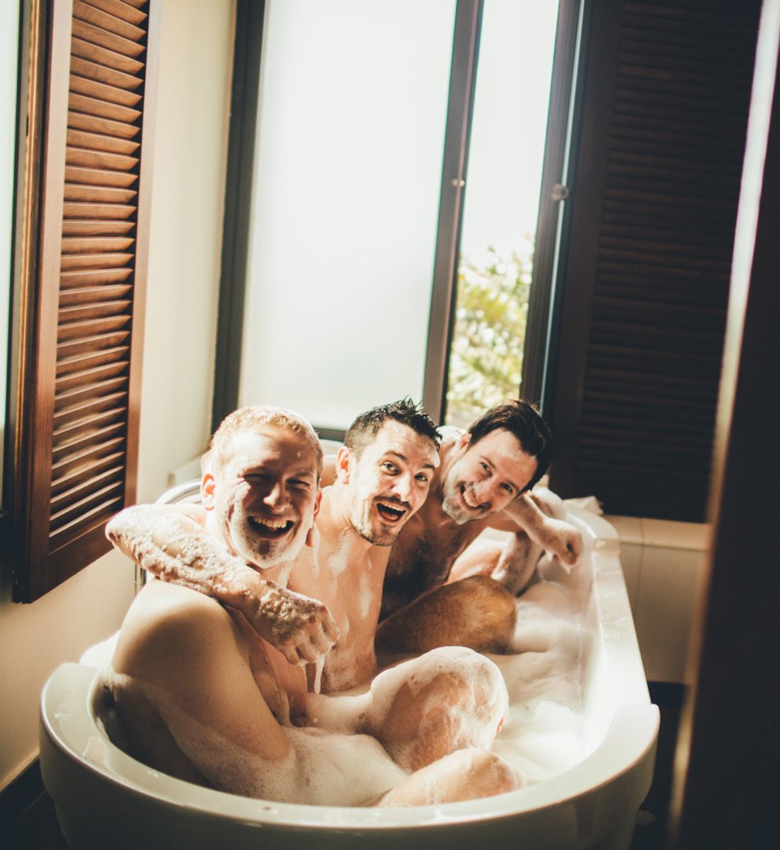 Amigos riendo dentro de una bañera con espuma en los preparativos previos a la boda